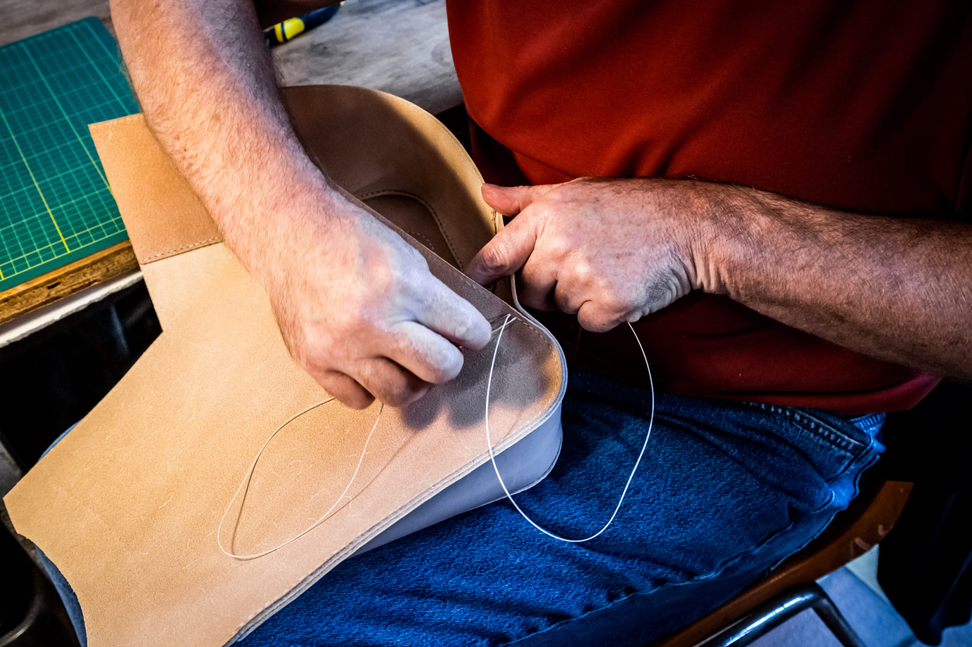 Gros plan sur les mains cousant un fourreau en cuir