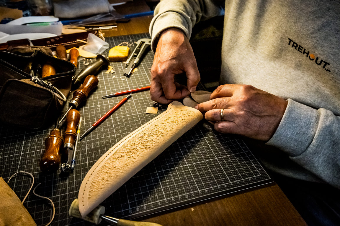 Mains travaillant les finitions d'un fourreau repoussé